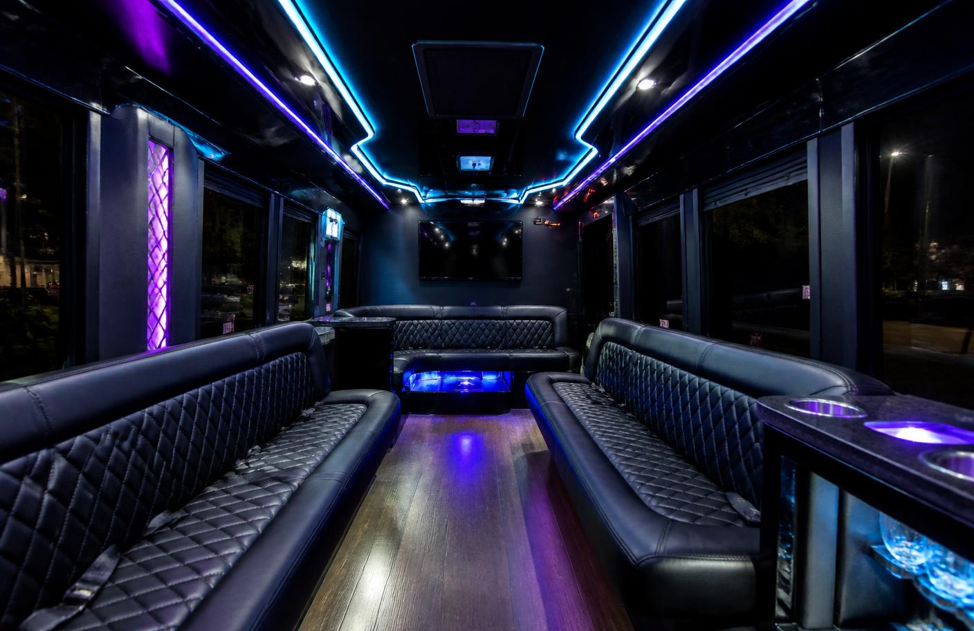 Interior of a Vibe Party Bus with wraparound leather seating and LED lighting